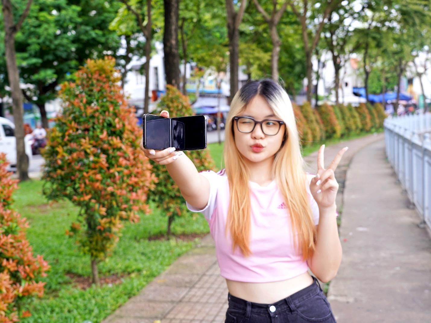 A person holding up a phone and making a peace signDescription automatically generated